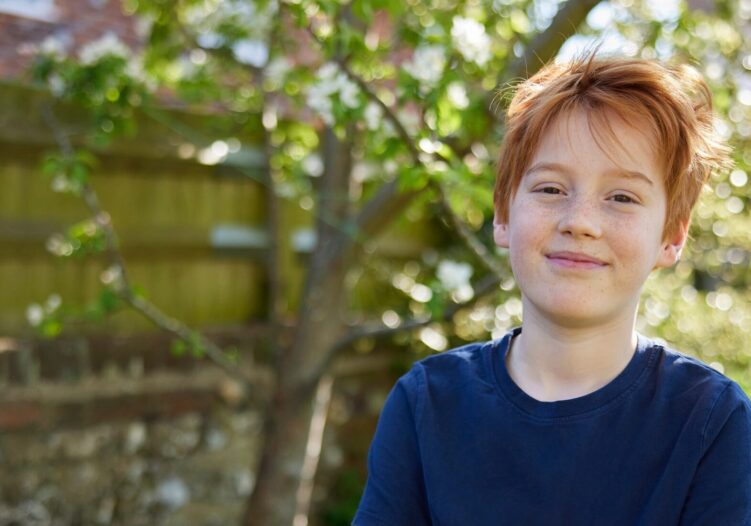 Boy standing with his arms folded in the garden