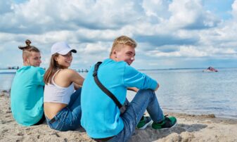 Three teenagers sat on the beach